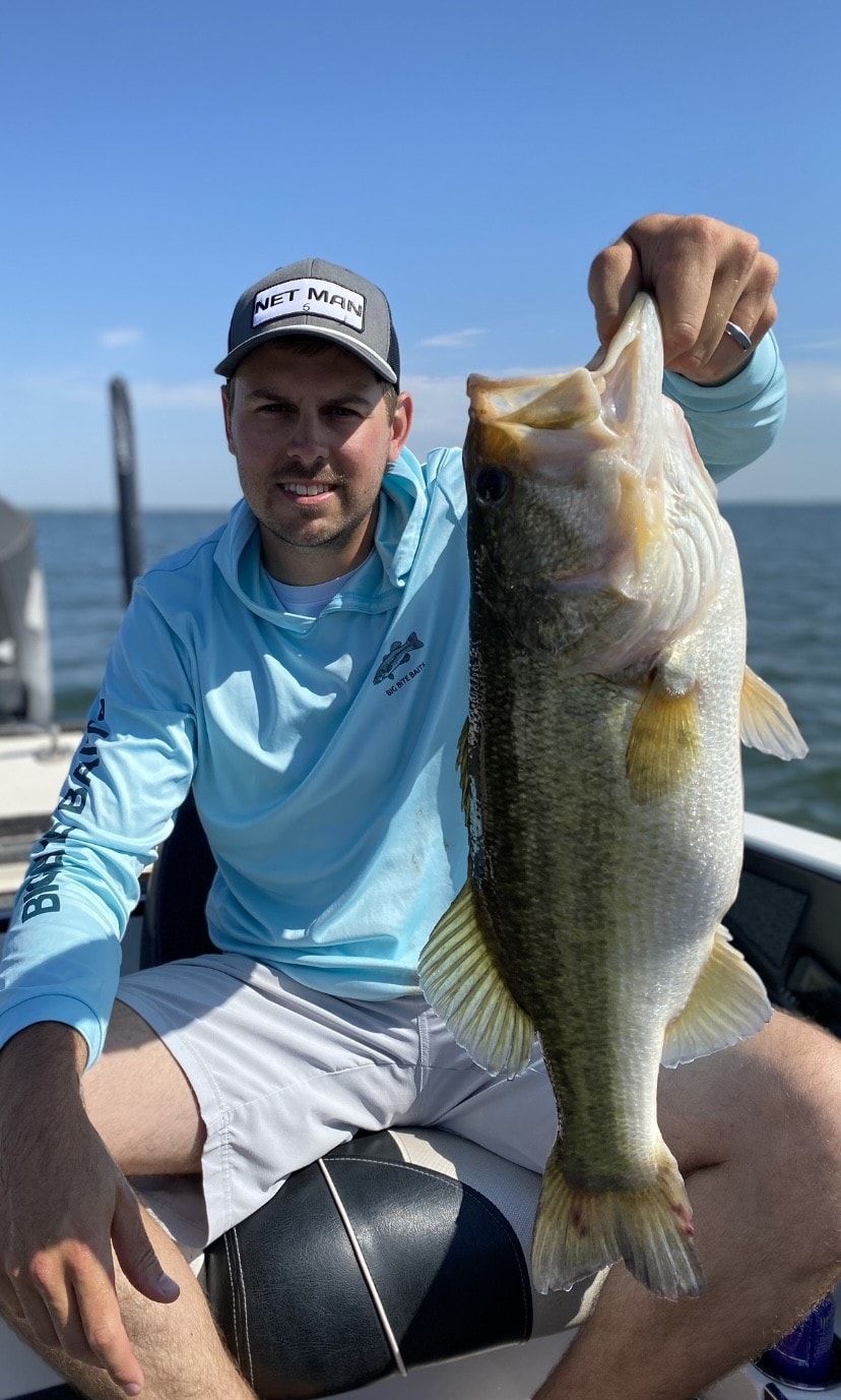 Man in Net Man cap holding big bass on sunny day on Lake Falcon