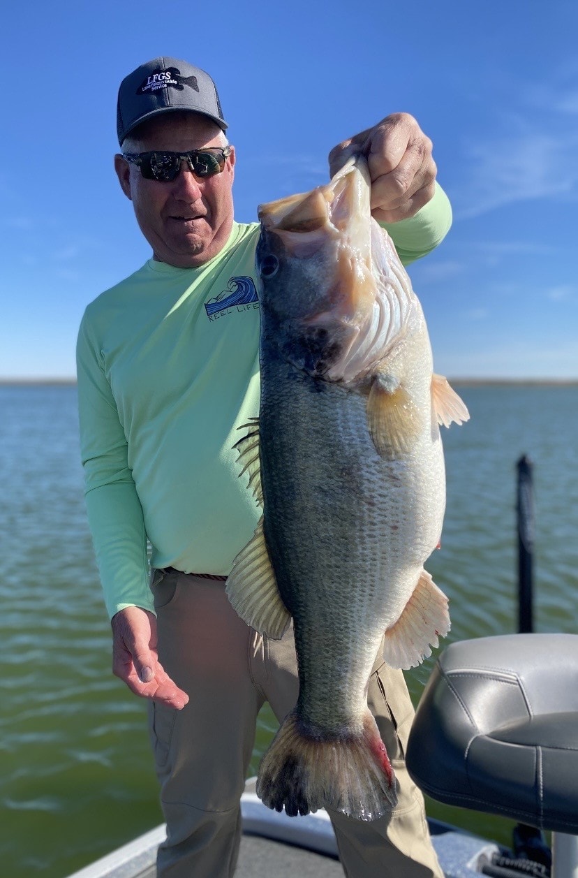 Angler in LFGS cap holding bass by the lip
