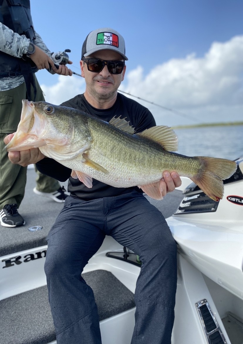 Man in black shirt holding big bass on boat
