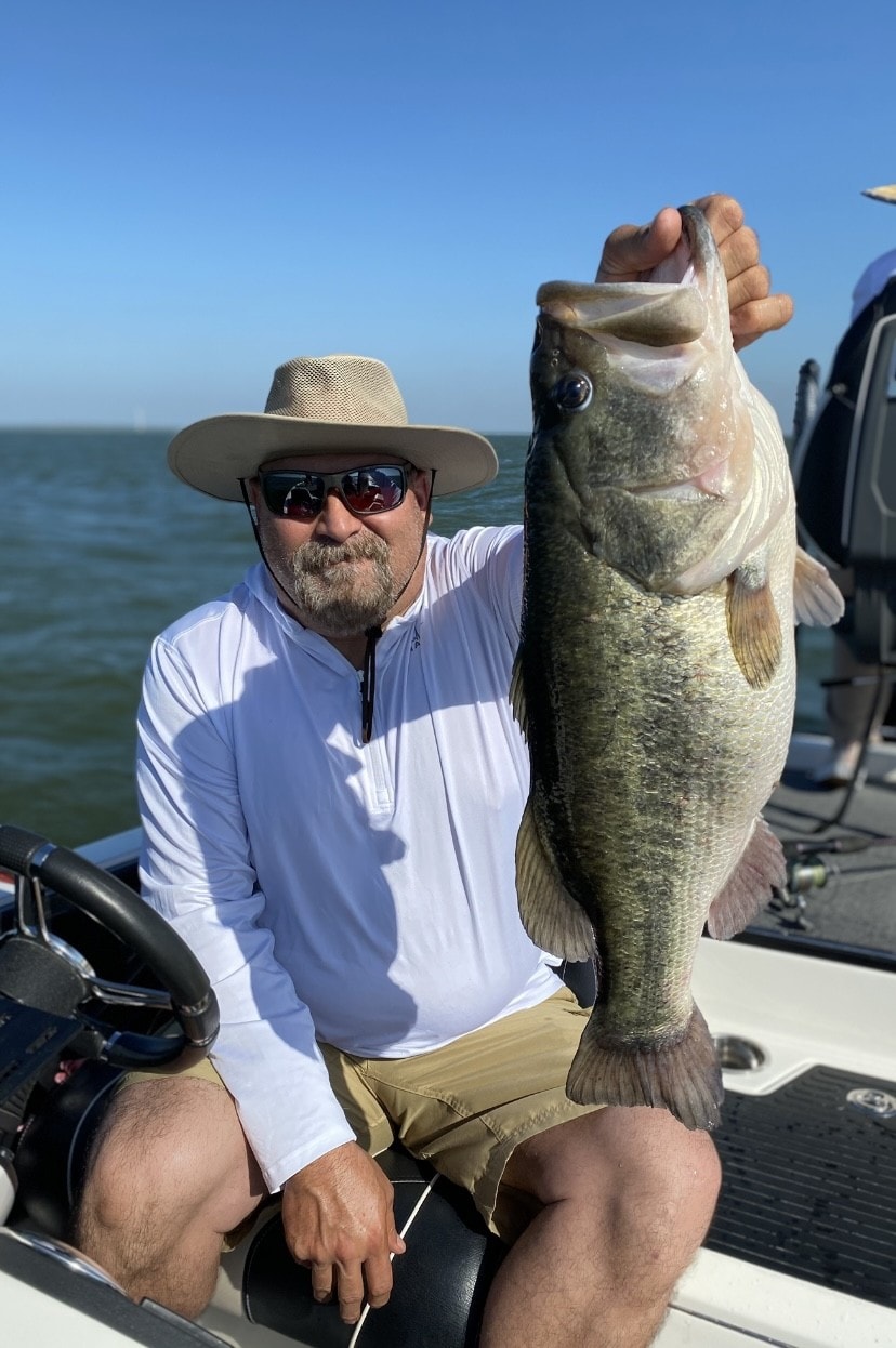 Man in white shirt holding big bass on sunny day