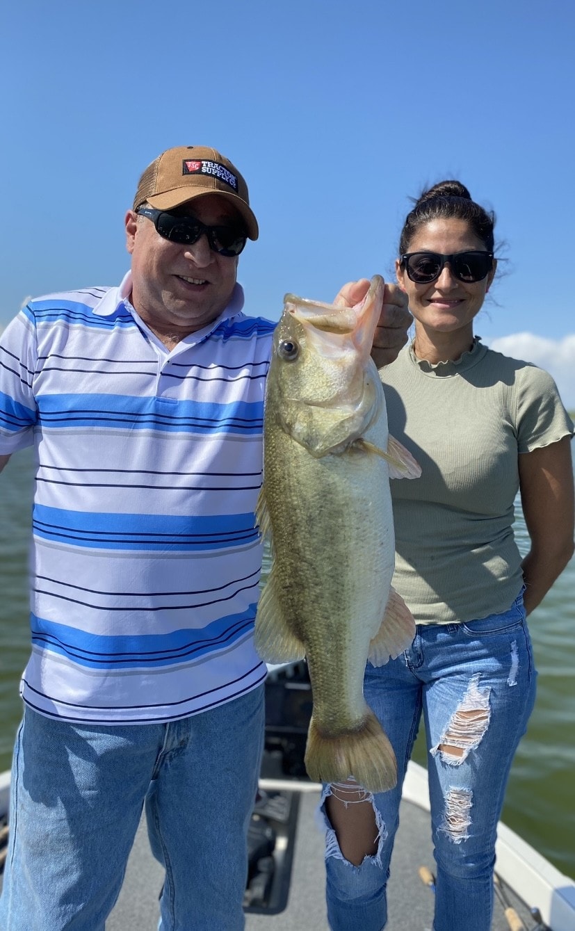 Man and woman holding bass on boat