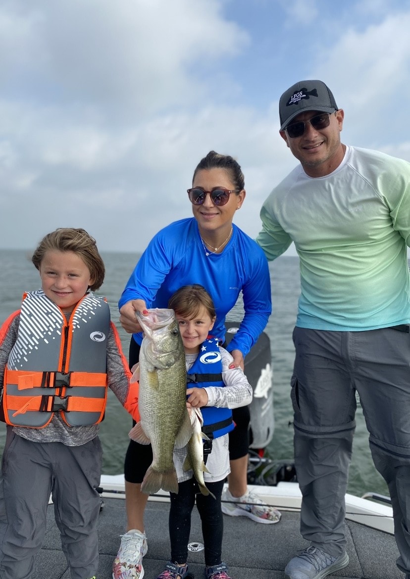 Family of four on boat with child holding bass