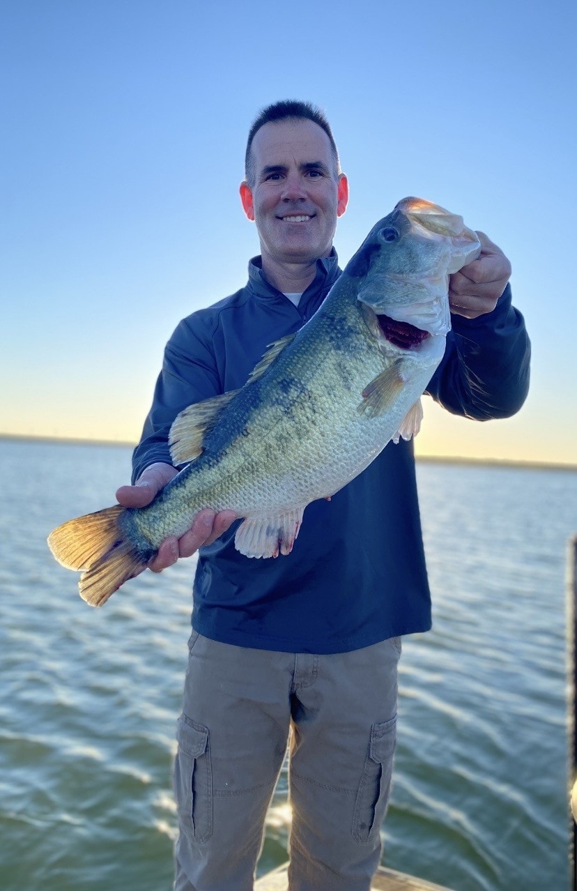 Angler holding bass at golden hour on the water