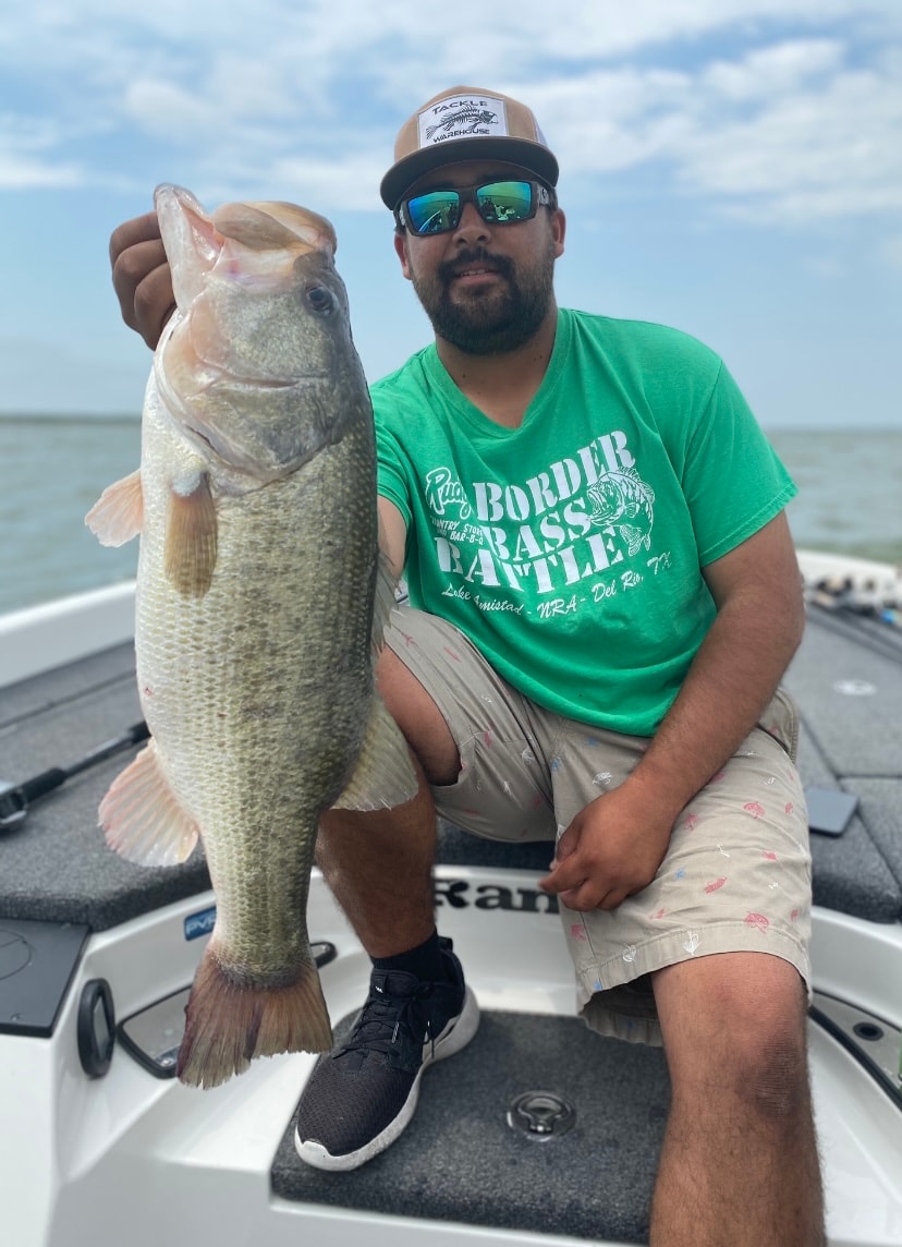 Man in green Border Bass Battle shirt holding large bass on boat