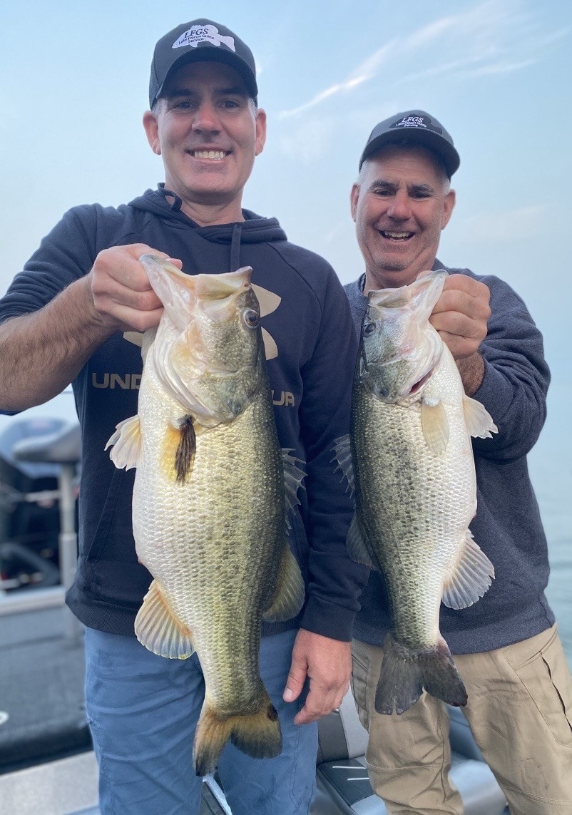 Two anglers each holding a big bass