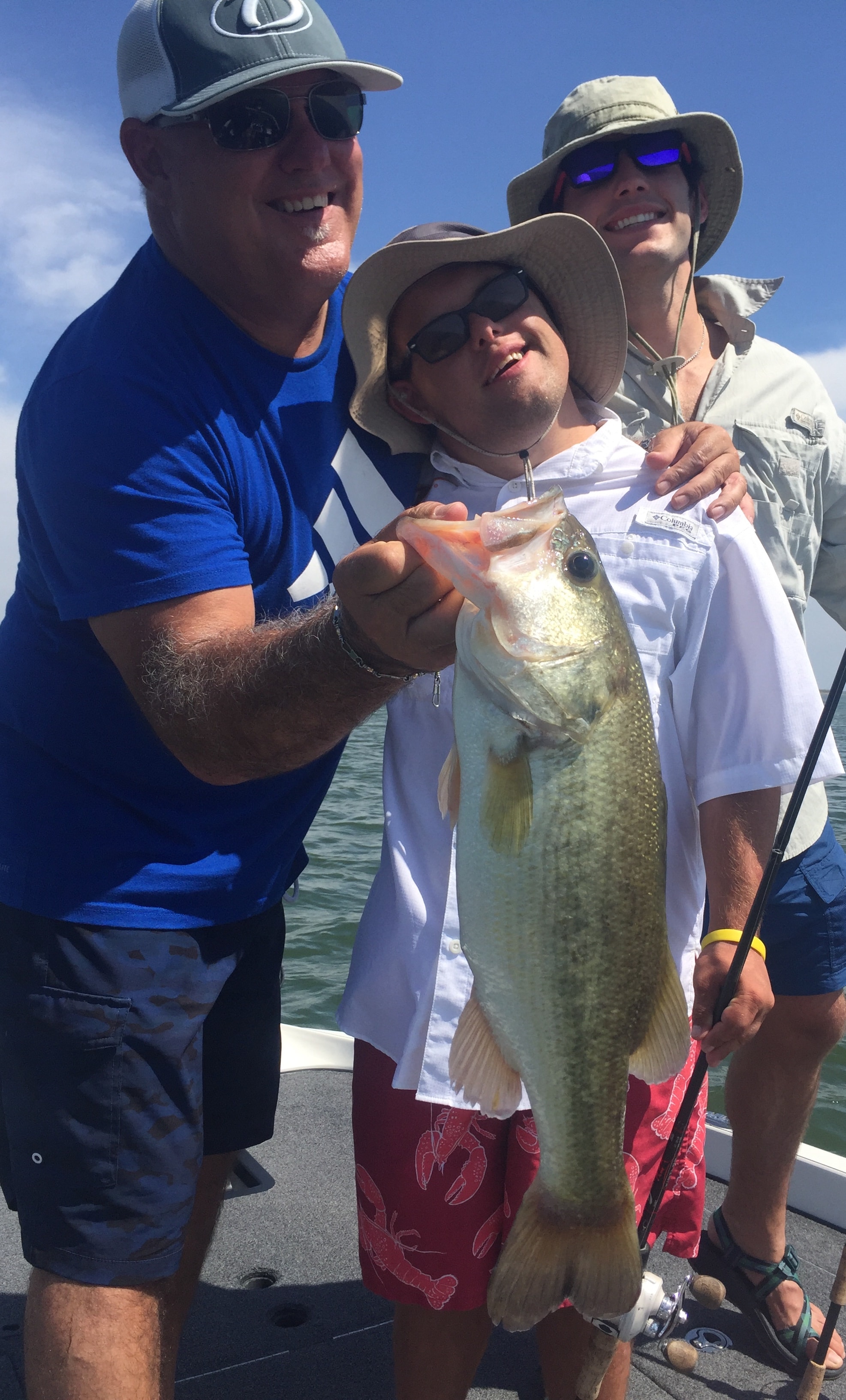 Three men on boat with bass on sunny day