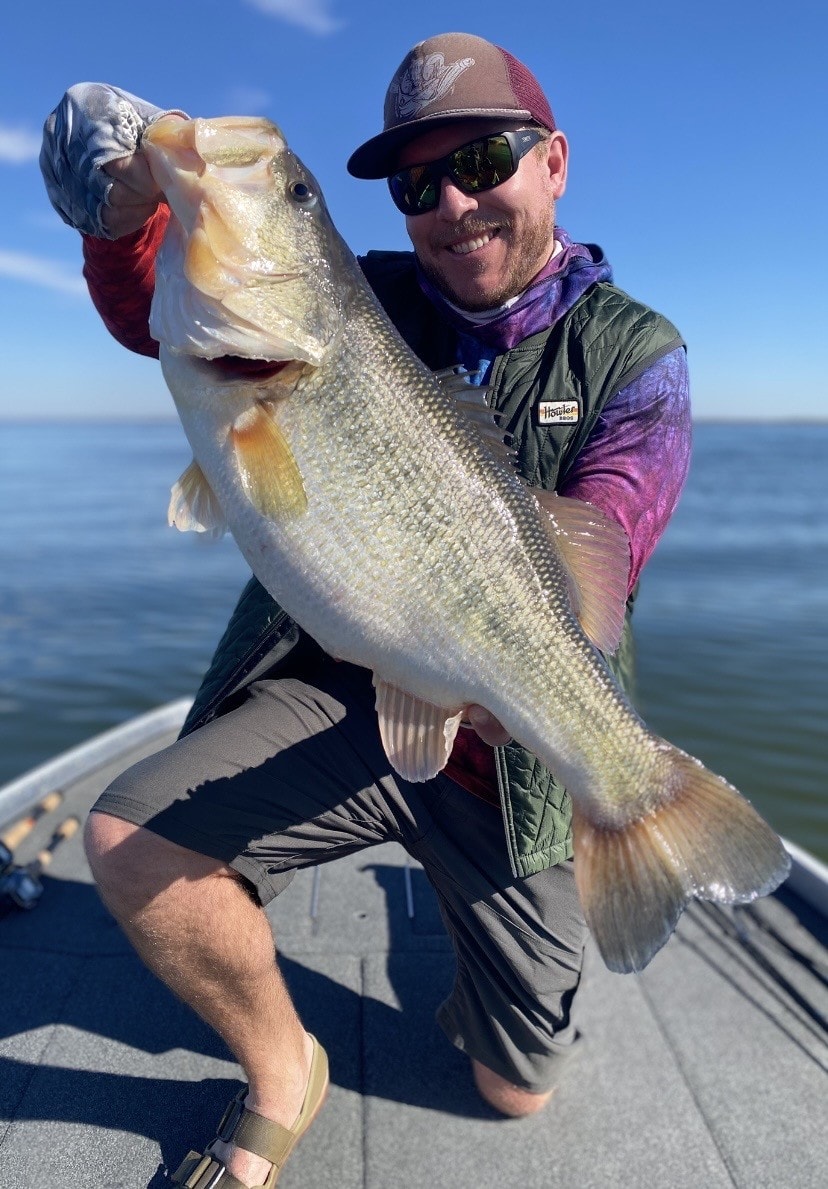 Angler holding massive largemouth bass on boat