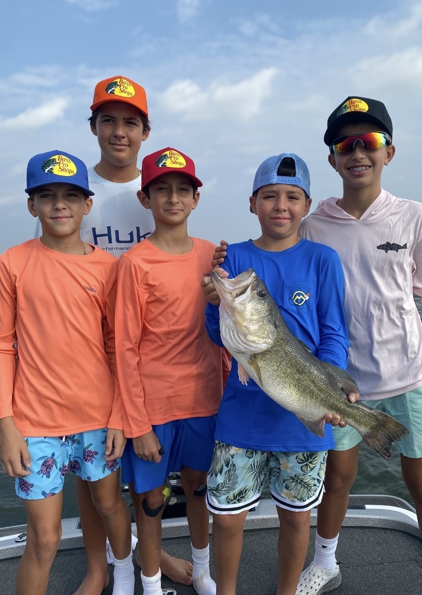 Five kids on boat with a bass catch