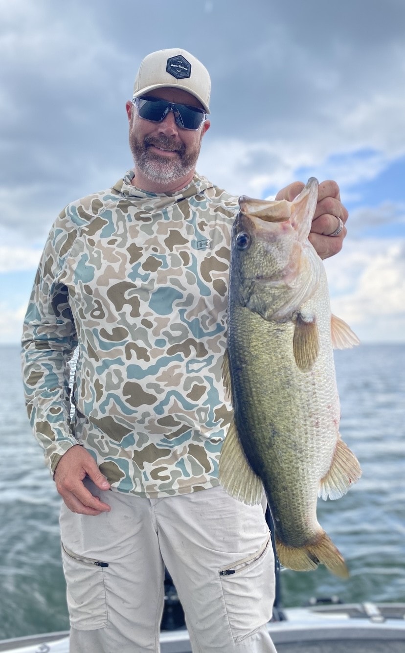Angler in camo hoodie holding big bass