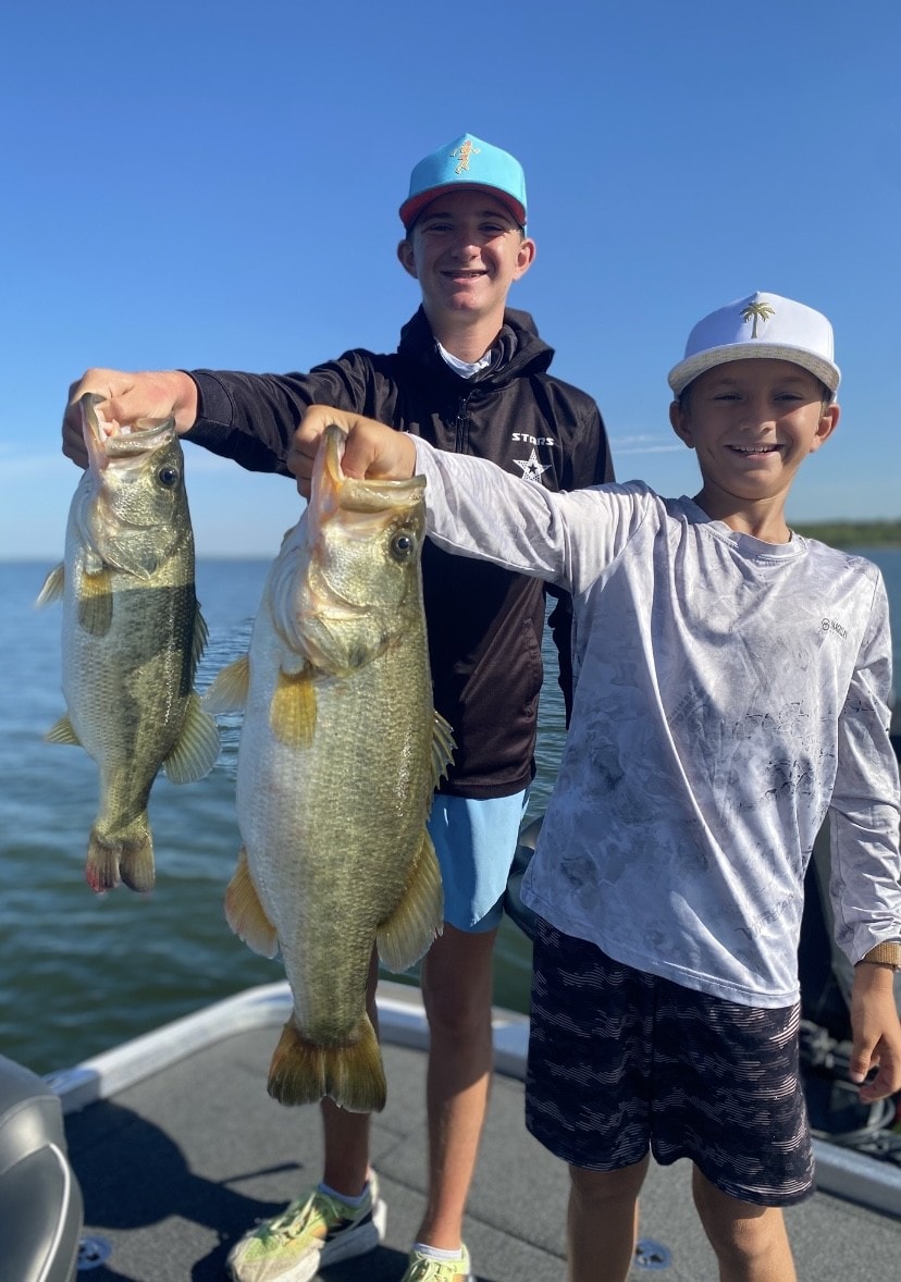 Two kids holding multiple bass on Lake Falcon