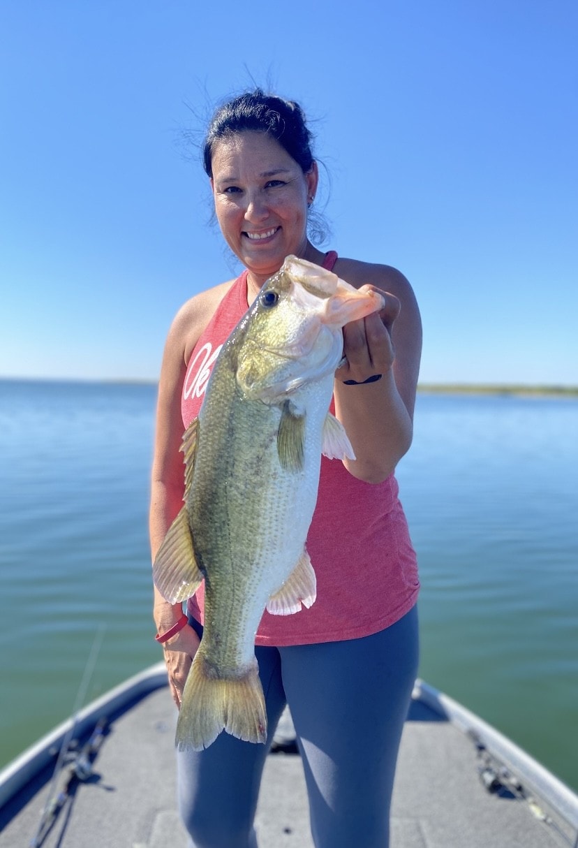 Woman holding bass on sunny day on the lake