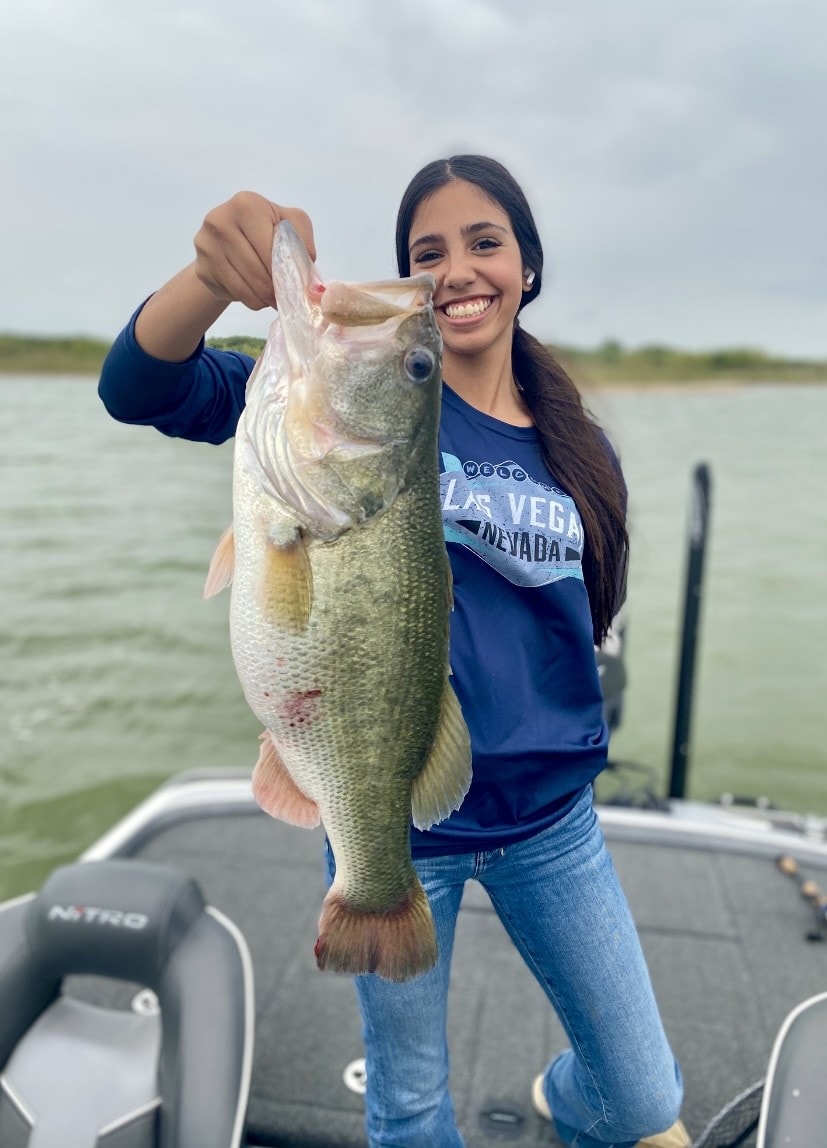 Woman in Las Vegas shirt holding big bass on Nitro boat