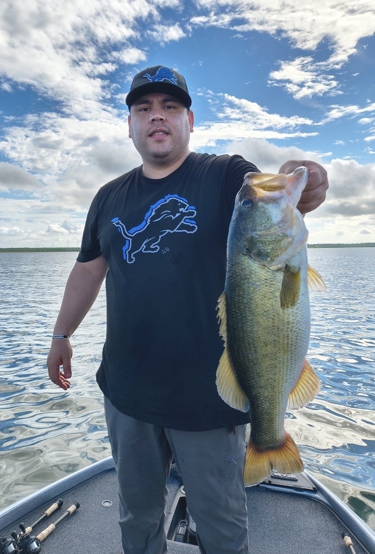 Man in Detroit Lions shirt holding bass on cloudy day