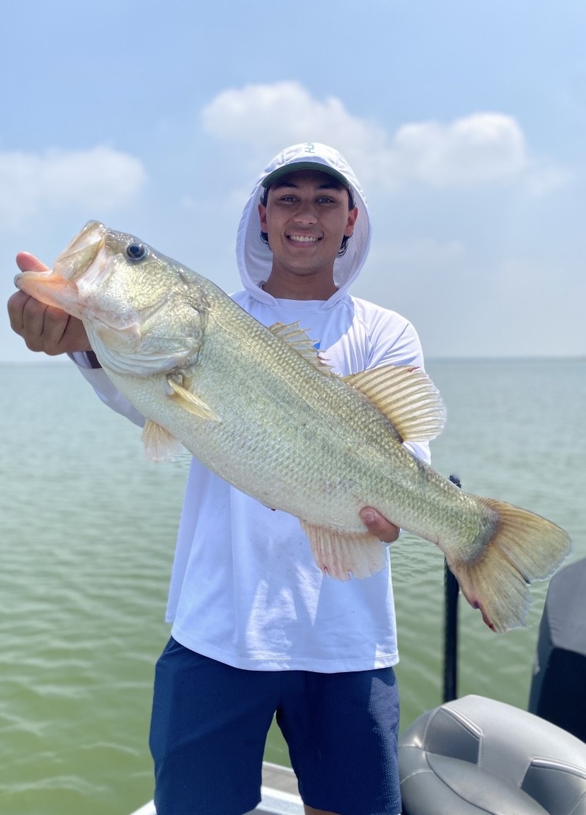 Young man in white hoodie holding large bass