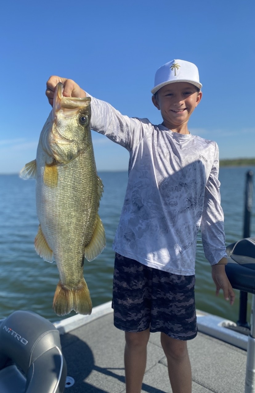 Young boy in white palm tree cap holding bass on Nitro boat