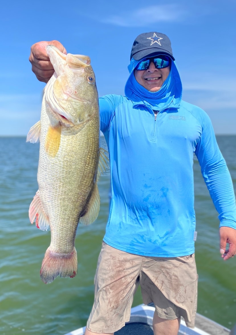 Man in blue Cowboys cap and hoodie holding bass