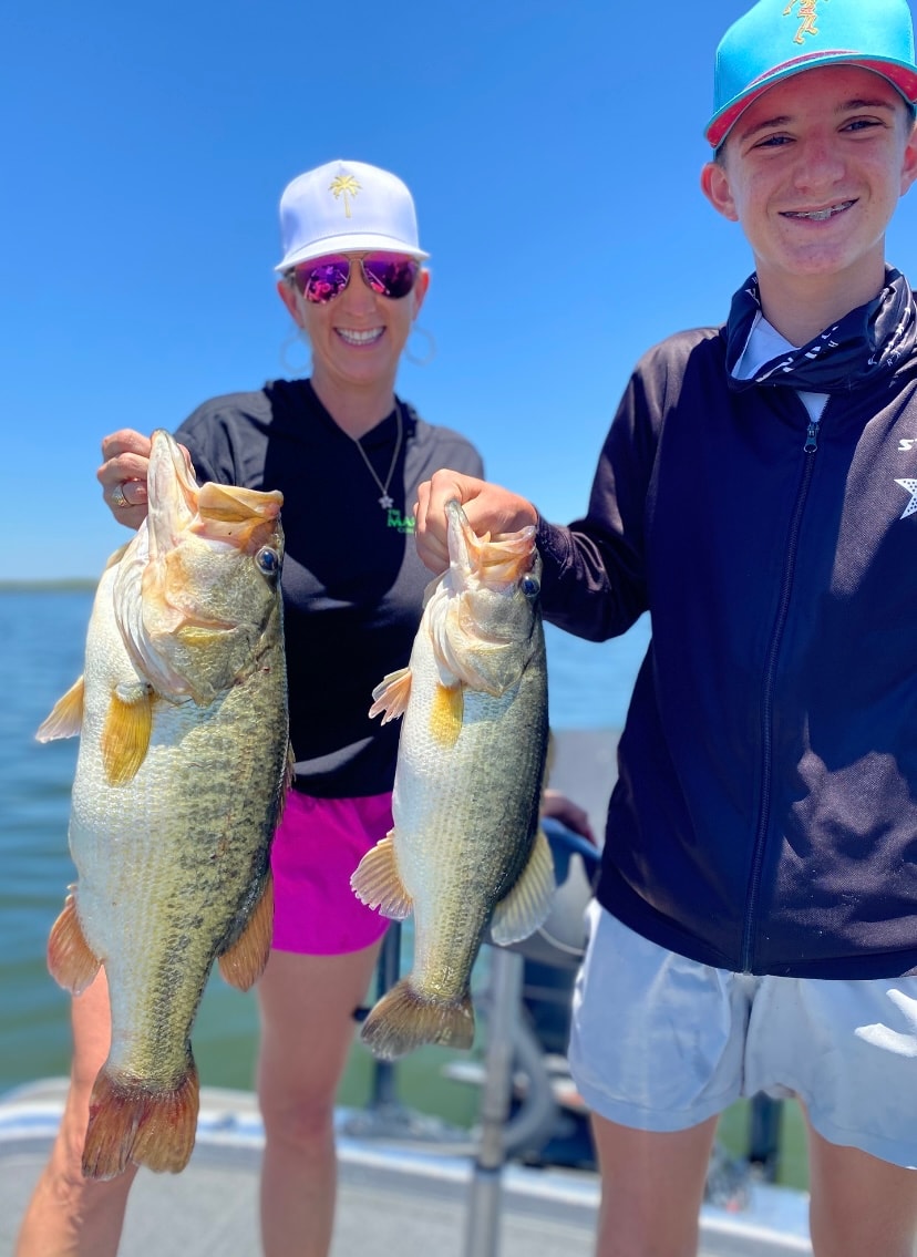 Woman and teen holding two big bass on sunny day