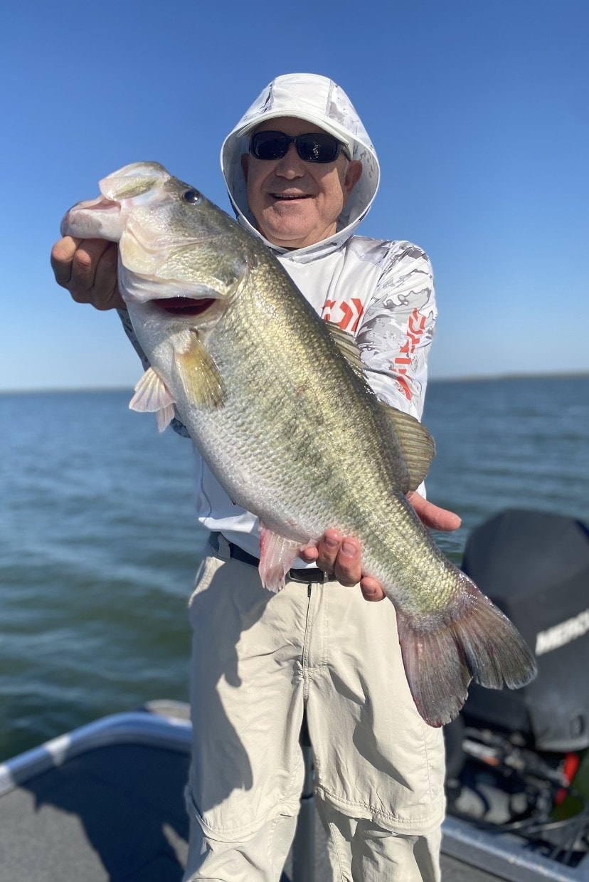 Older man in white sun hat holding big bass on sunny day