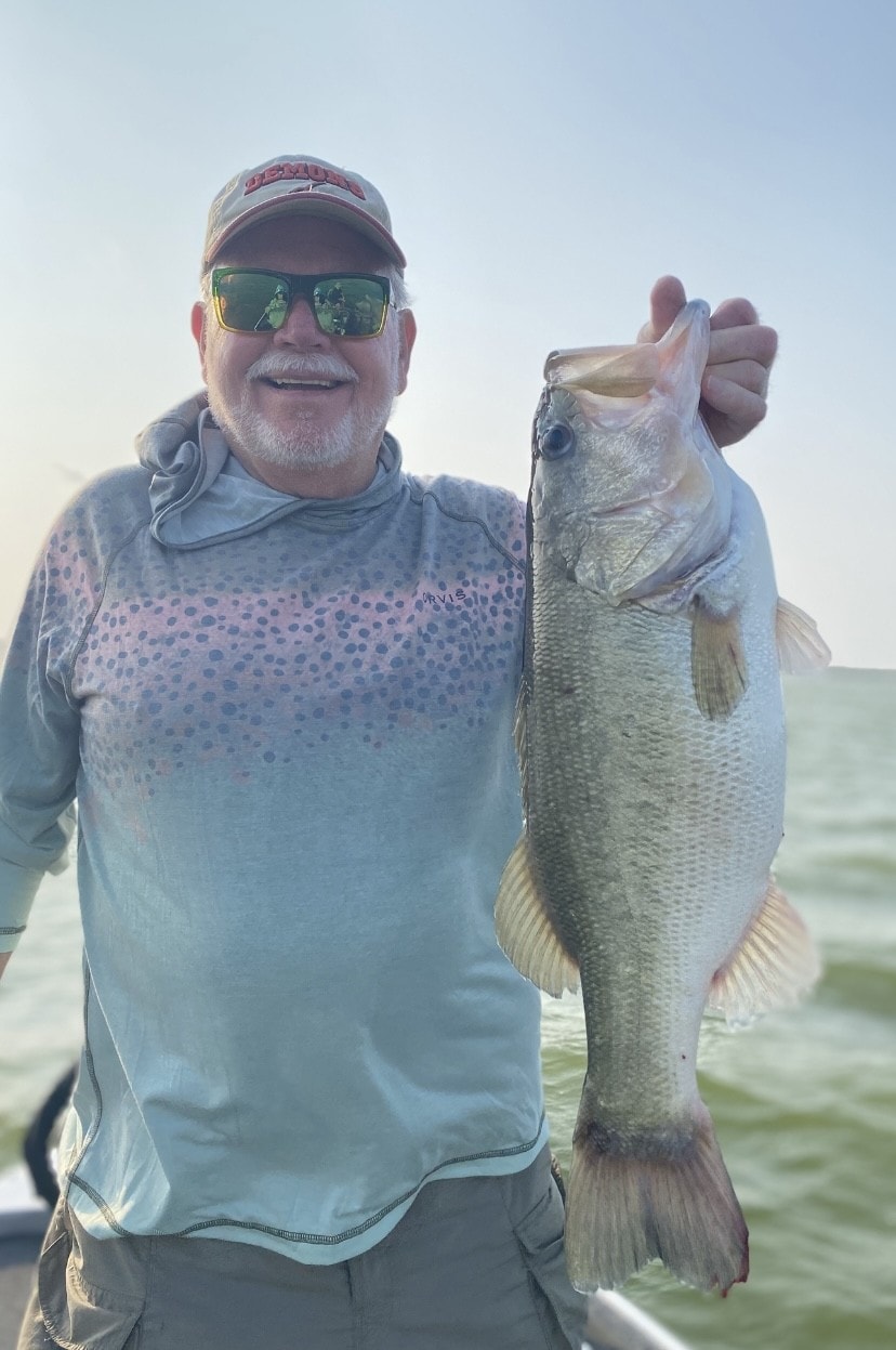 Man in Orvis shirt holding bass at golden hour