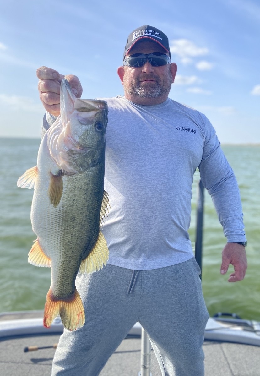 Man in Magellan shirt holding big bass on cloudy day