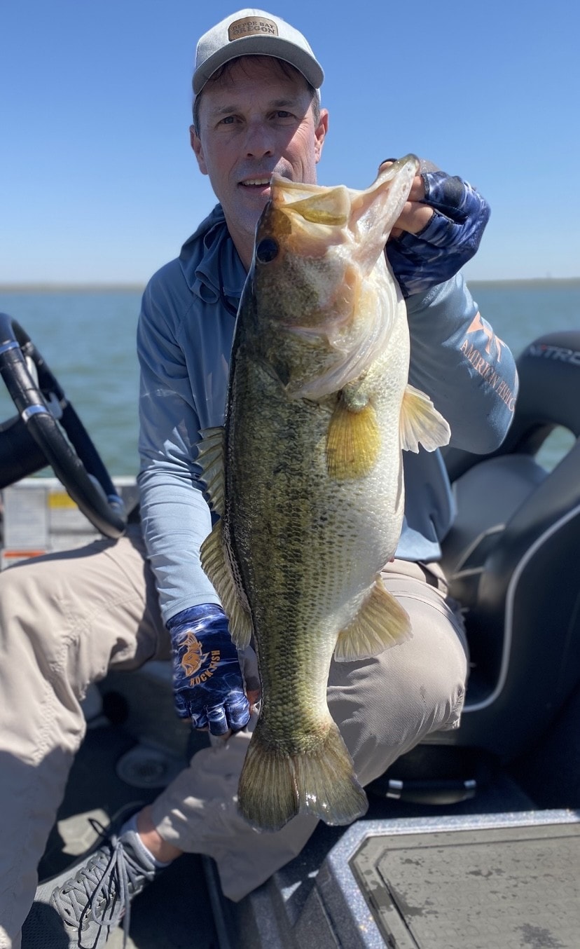Man in Coos Bay Oregon cap holding massive bass on Nitro boat