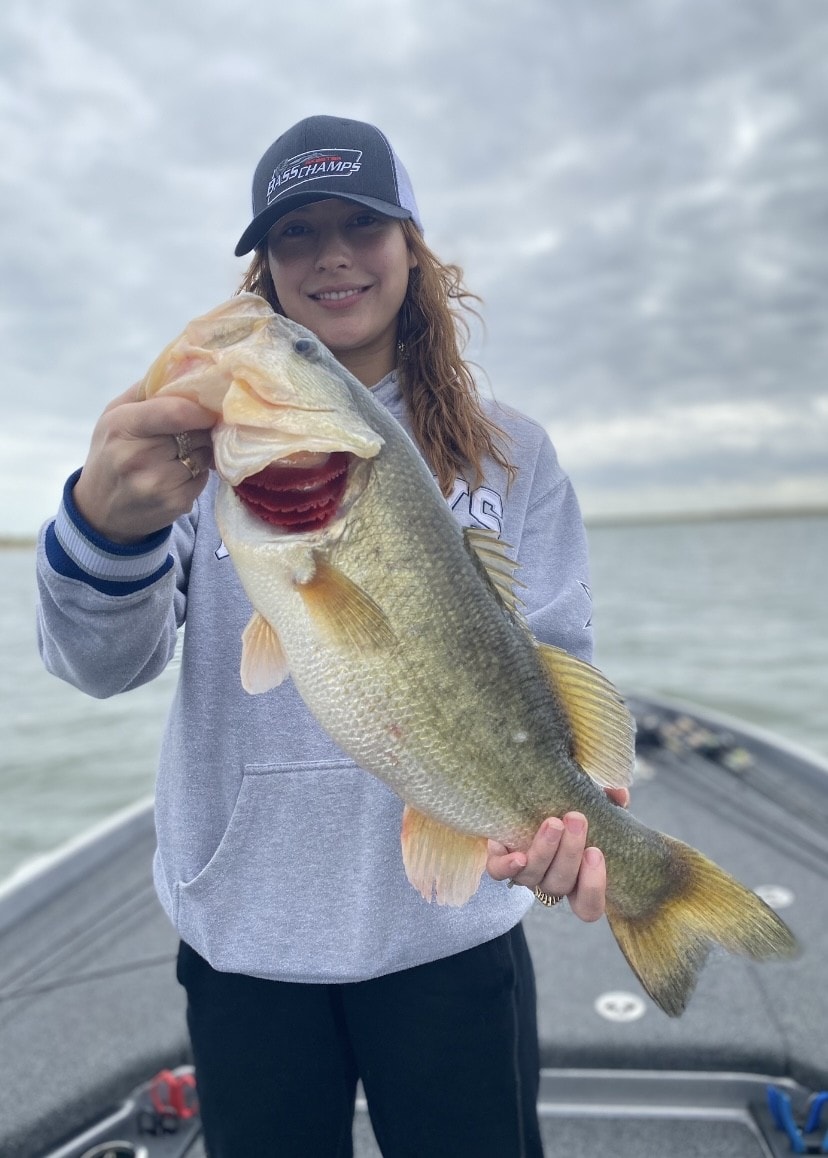 Girl in Bass Champs cap holding bass on overcast day