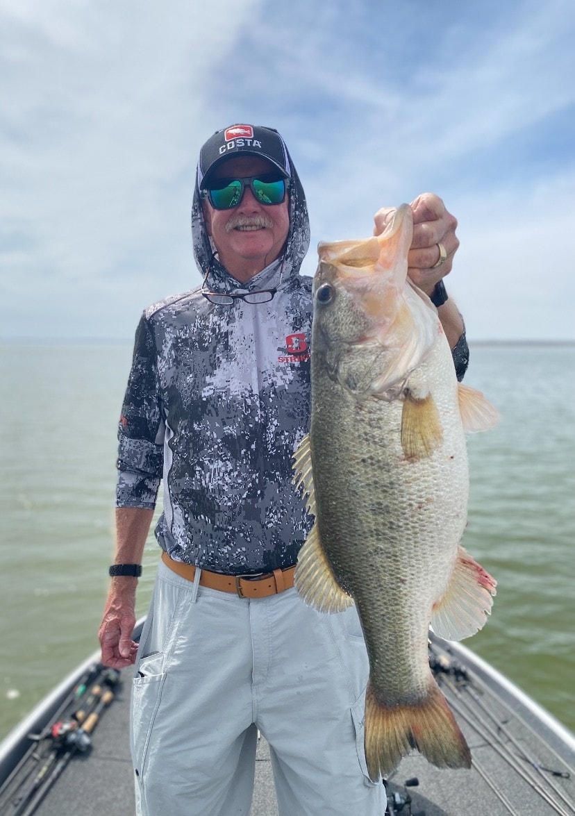 Man in Costa cap and camo hoodie holding trophy bass