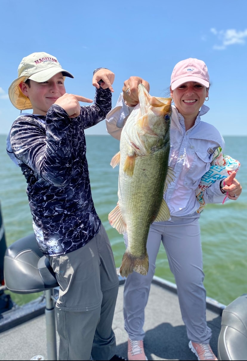 Boy and woman pointing at big bass on sunny day on Lake Falcon