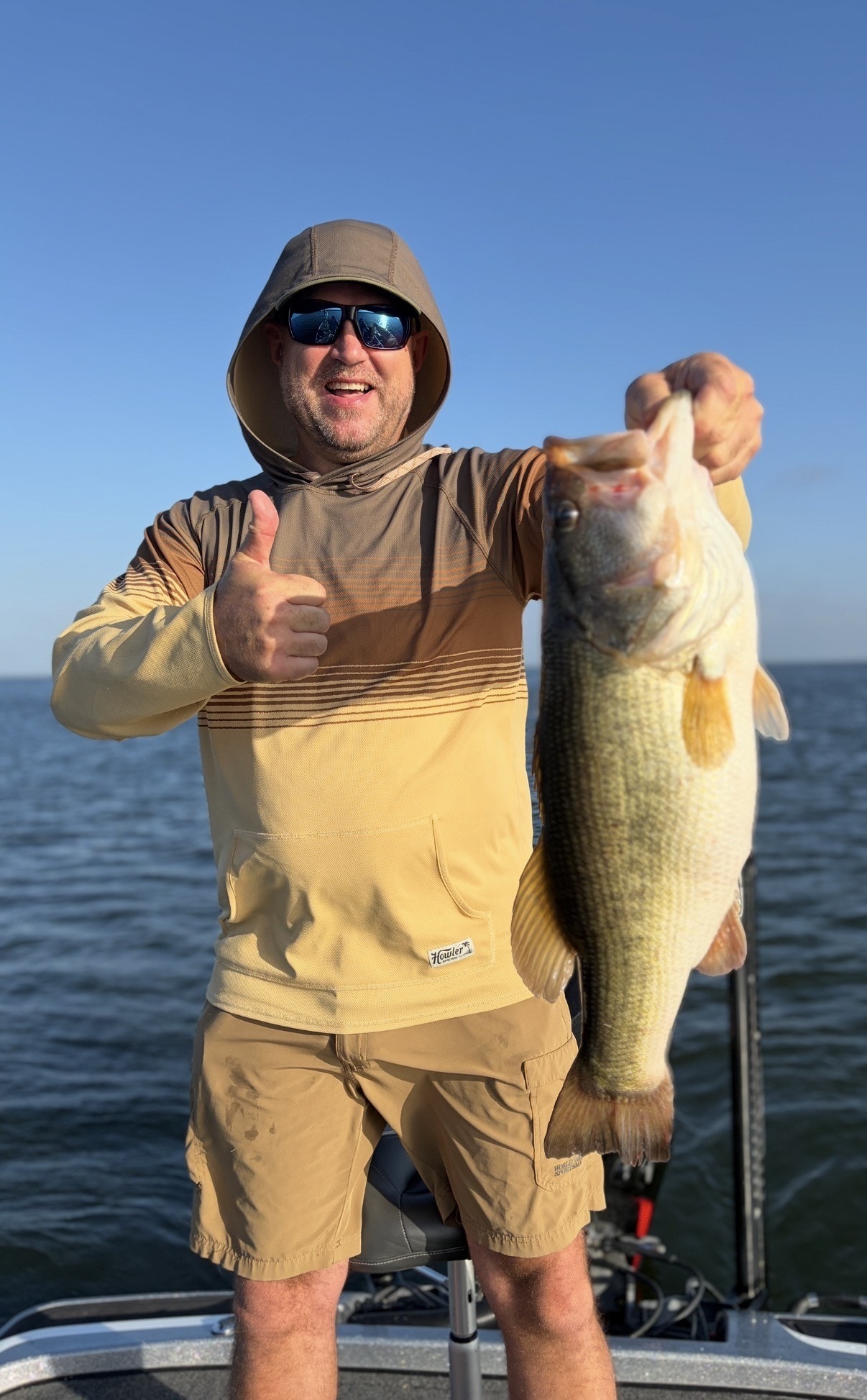 Happy angler with big bass thumbs up