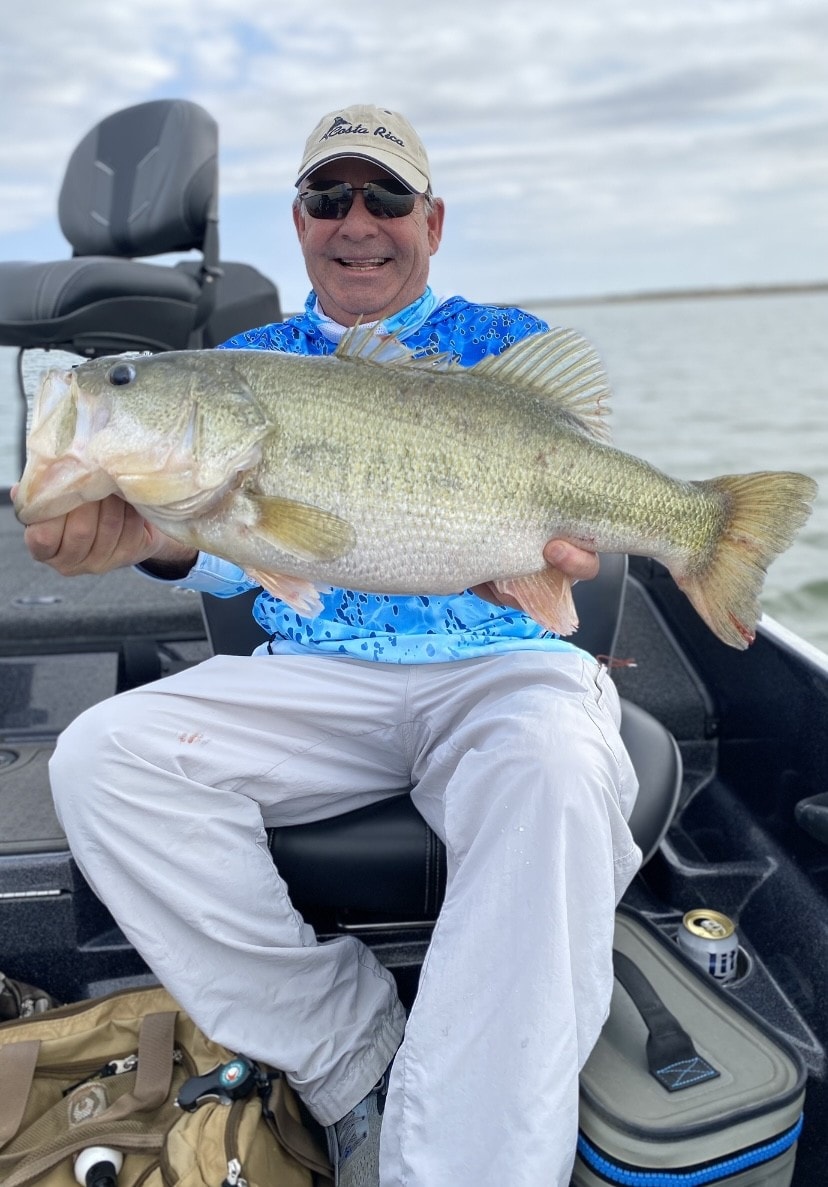 Man in Costa Rica cap holding massive bass on cloudy day on Lake Falcon